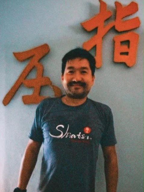 Patrick Yano na clínica em Porto Alegre, diante dos kanji 指圧 (shiatsu) na parede